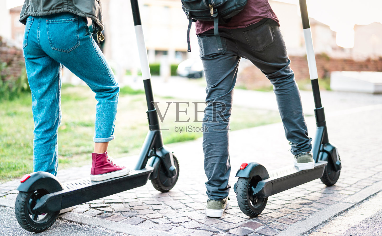 近距离的城市通勤者使用电动滑板车在城市公园-千禧一代的学生骑新的现代生态交通工具-绿色生态能源概念与零排放-明亮的复古过滤器照片摄影图片