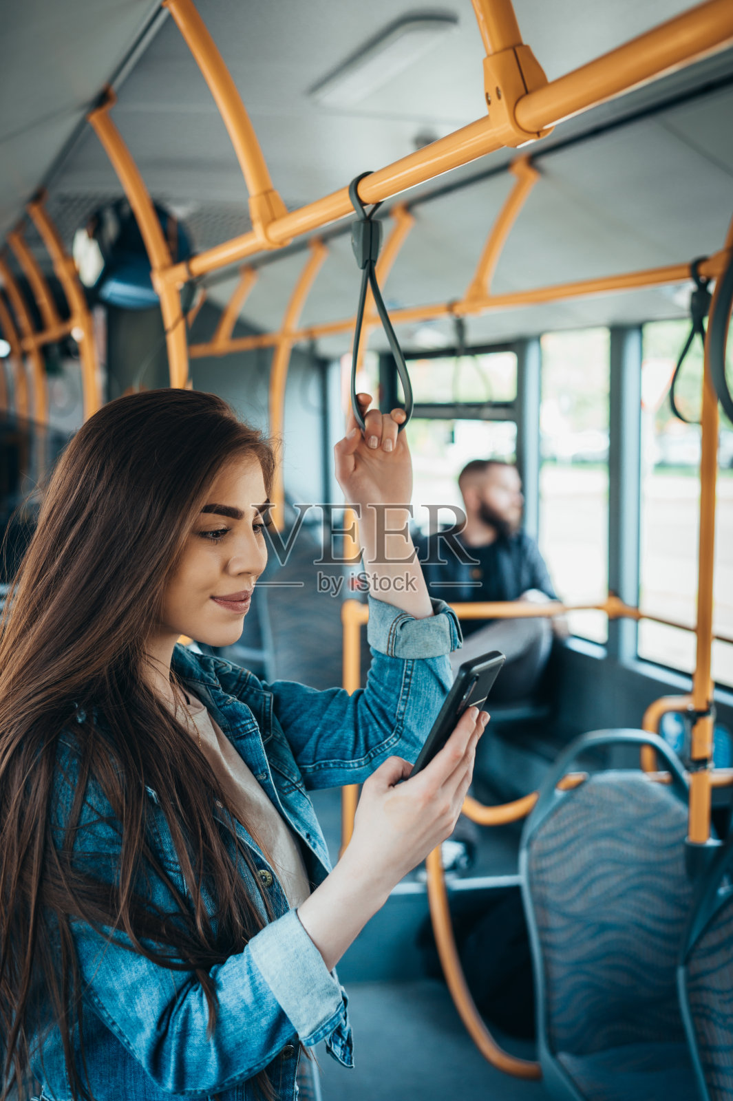 一个女人独自站在公交车上用智能手机照片摄影图片
