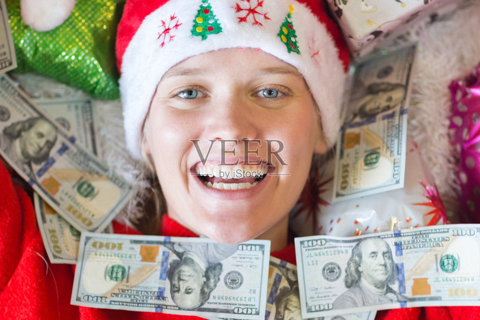 快乐的女人在圣诞节被现金和礼物包围着。照片摄影图片