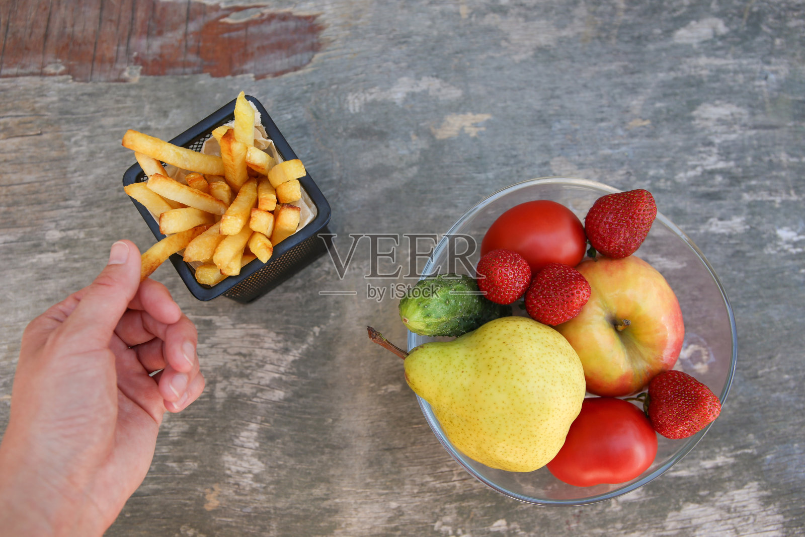 薯条，水果，蔬菜放在旧的木头背景上。概念选择正确的营养或垃圾食品。前视图。照片摄影图片