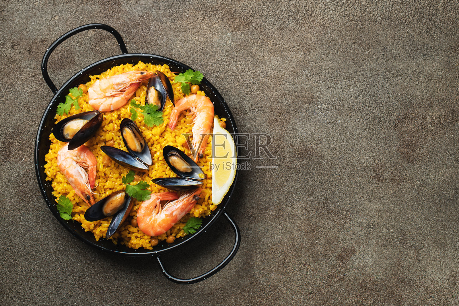 传统的西班牙海鲜饭与鹰嘴豆，虾，贻贝，鱿鱼在棕色混凝土背景。顶部视图与复制空间照片摄影图片