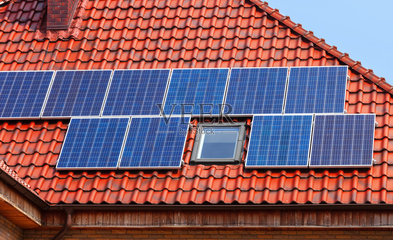 红瓦屋顶上的现代太阳能电池板。照片摄影图片