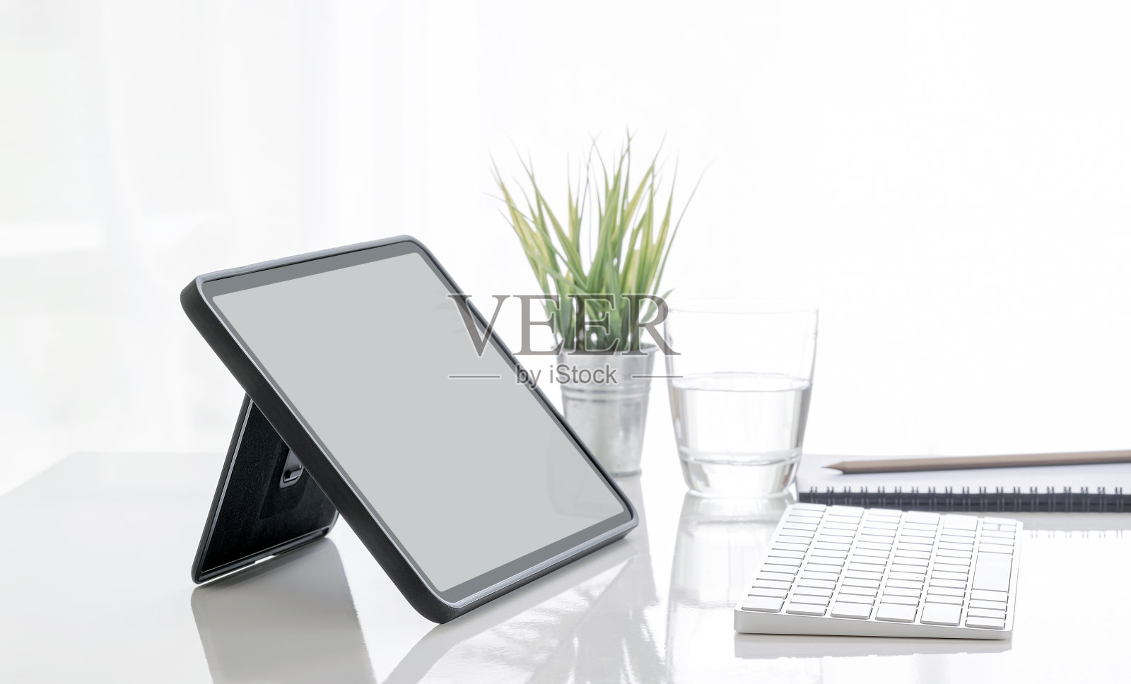 黑屏平板电脑在支架上和键盘在白色桌子上。照片摄影图片