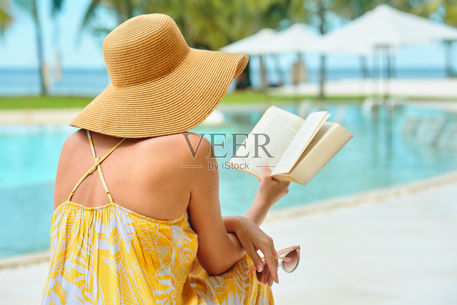度假海滩夏季度假概念。穿着黄色衣服的漂亮女人在海滩上休息看书照片摄影图片