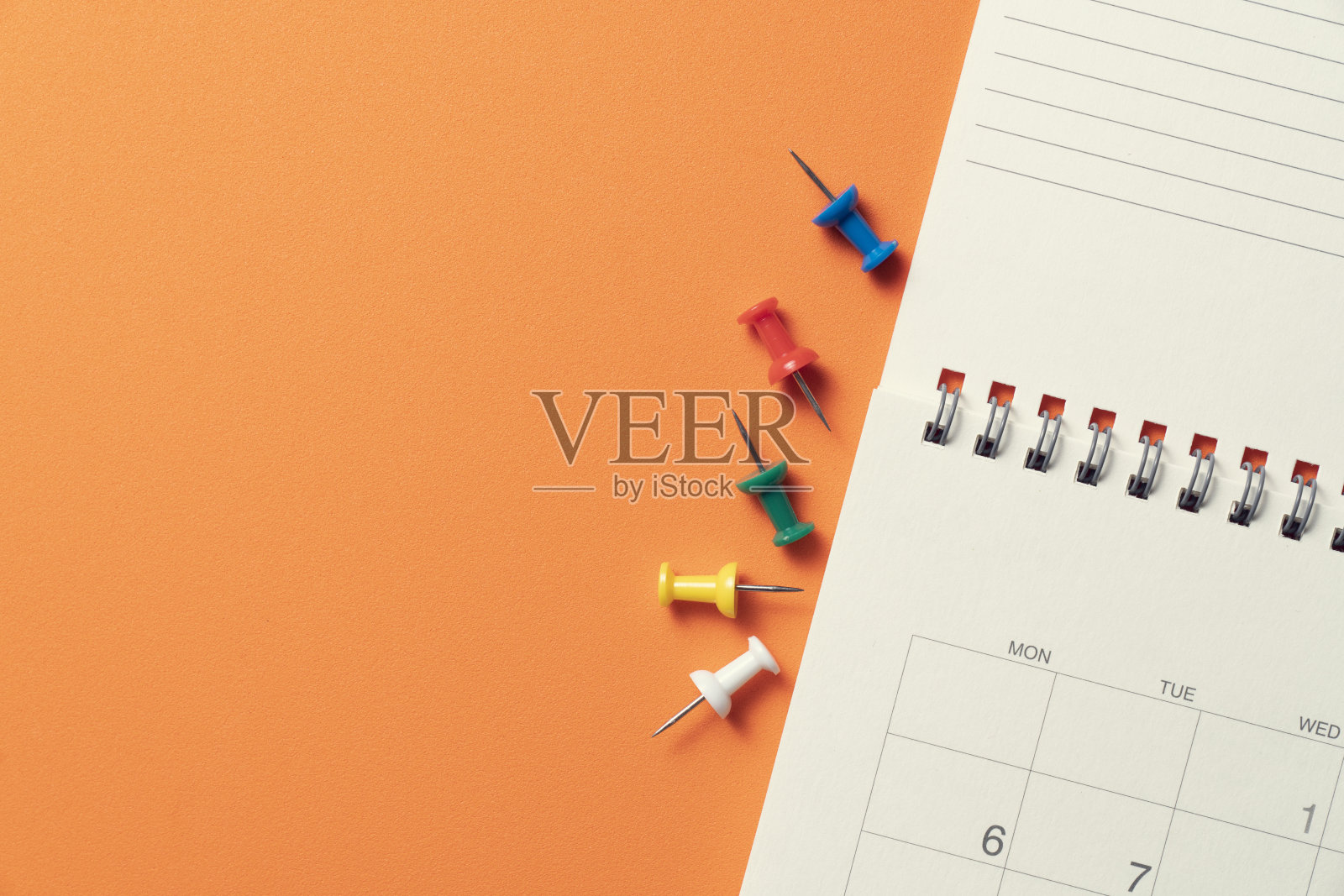 近距离的日历和大头针放在橙色的桌子背景上，计划商务会议或旅行计划的概念照片摄影图片