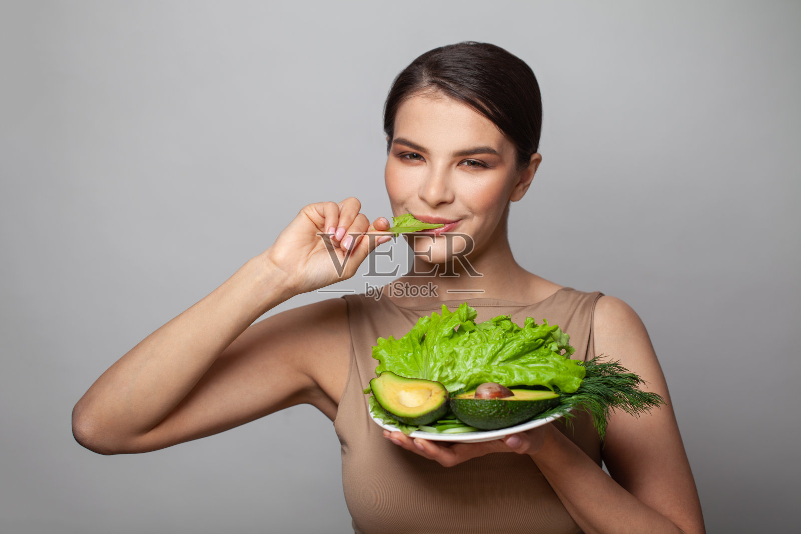 年轻健康的女人吃蔬菜和香草。饮食。节食的概念。健康食品。照片摄影图片