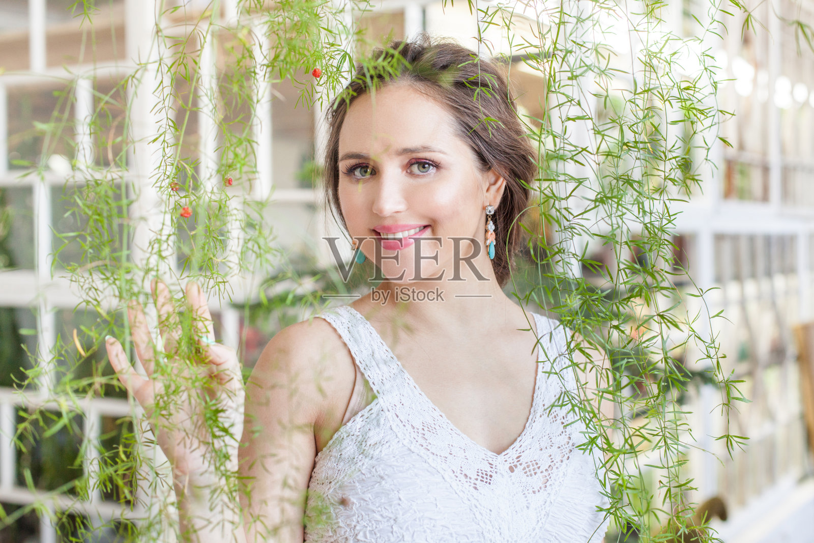 快活的漂亮女人黑发微笑在绿色的树叶背景照片摄影图片