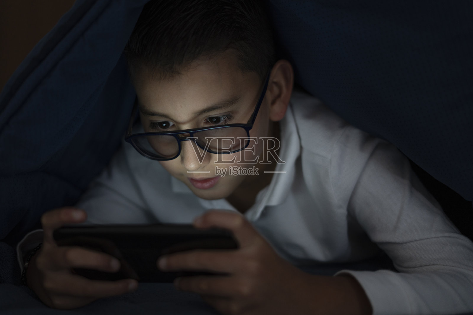 拉丁男孩在房间里玩手机照片摄影图片