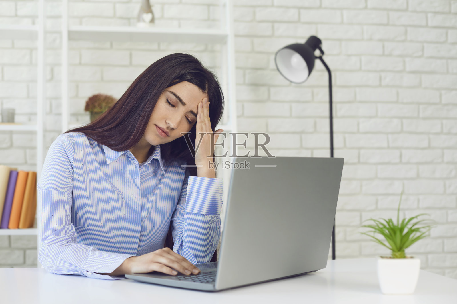 在家庭办公室里用笔记本电脑工作，劳累过度的女商人。学生正在为在线测试做准备照片摄影图片