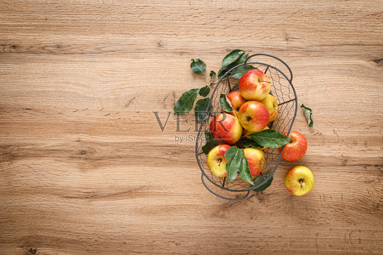 新鲜的红苹果与树叶在一个篮子在木制桌子的顶部视图照片摄影图片