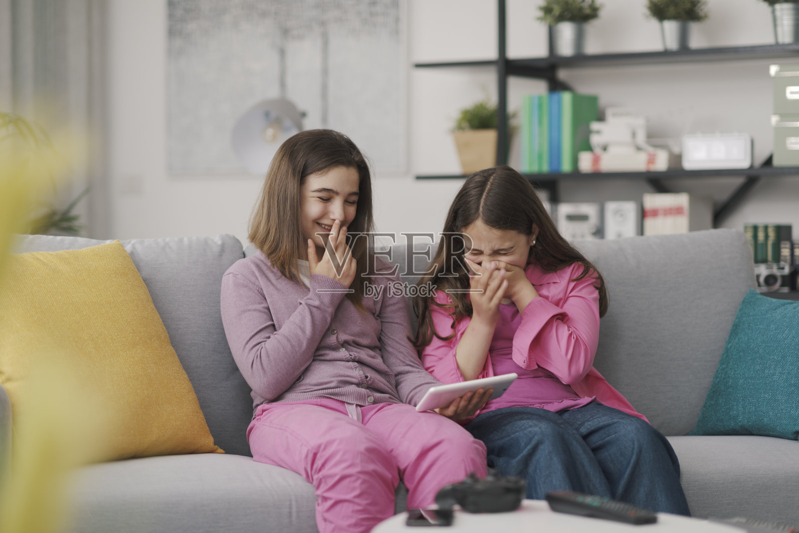 快乐的女孩坐在沙发上，连接着一个数字平板电脑照片摄影图片