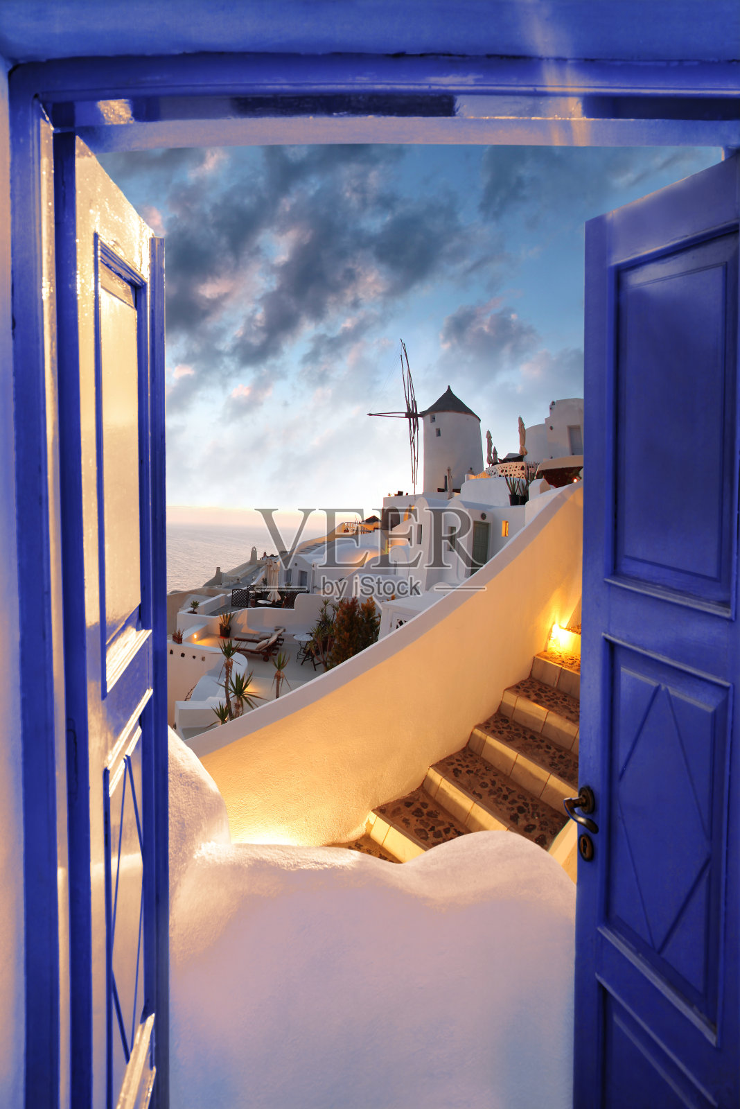 希腊伊亚村的圣托里尼岛，落日映衬着风车照片摄影图片