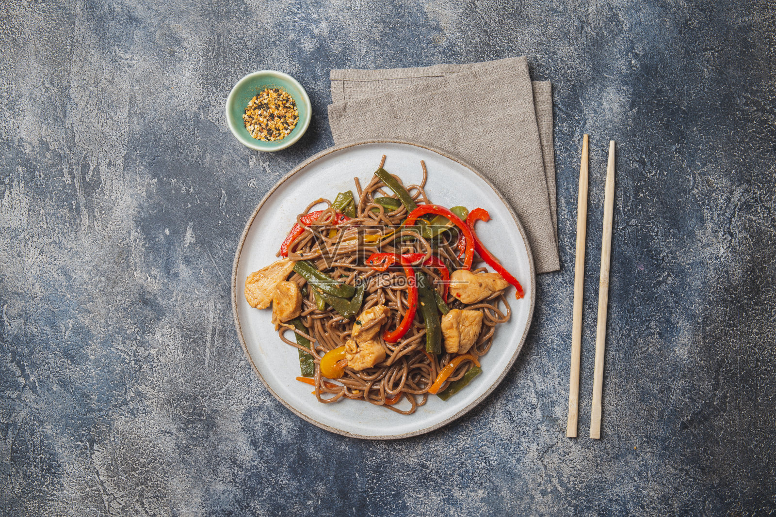 日本料理荞麦荞麦面，鸡肉和蔬菜胡萝卜，青椒和青豆，在深蓝底炒锅中照片摄影图片