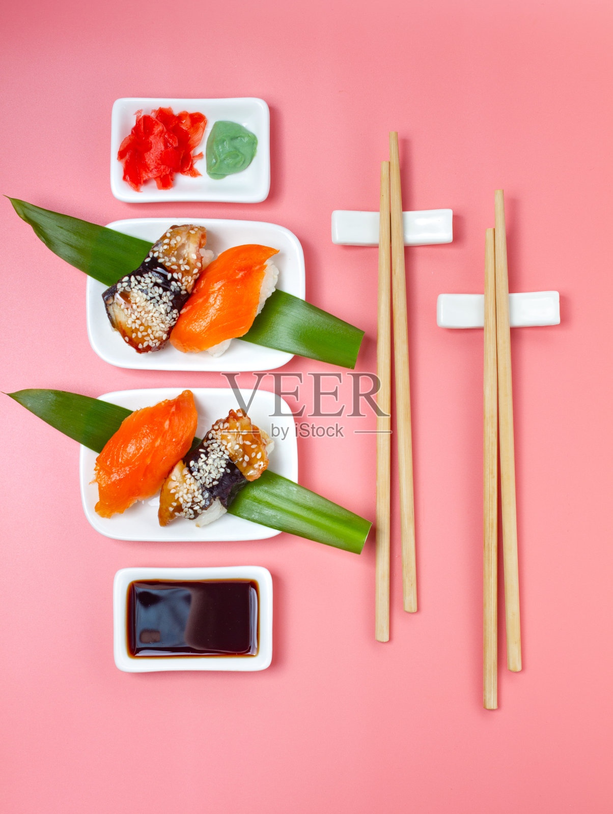 粉红色的极简主义背景下，搭配筷子和酱油的寿司。照片摄影图片