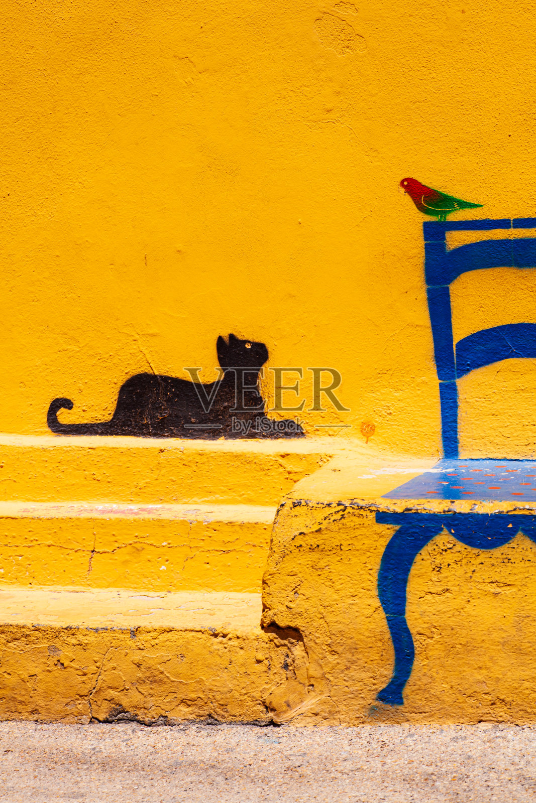 Linosa的墙上有一幅著名的插画:一只猫看着一只坐在椅子上的鸟照片摄影图片
