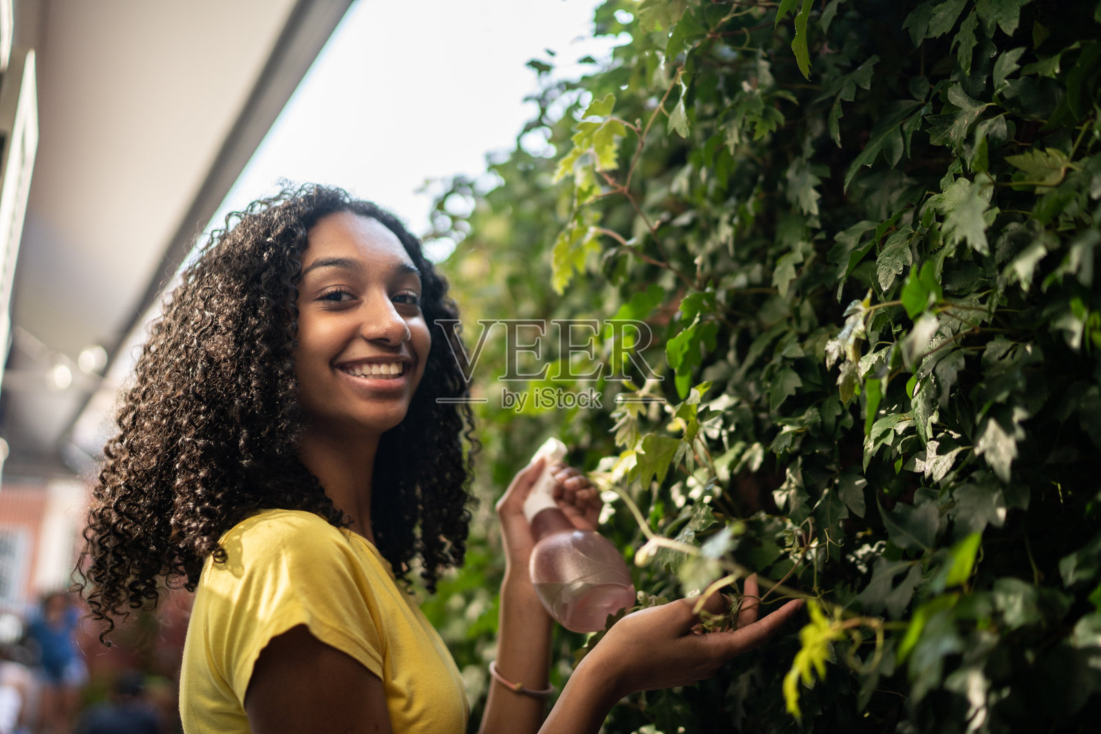 一个十几岁的女孩在户外浇灌植物的肖像照片摄影图片