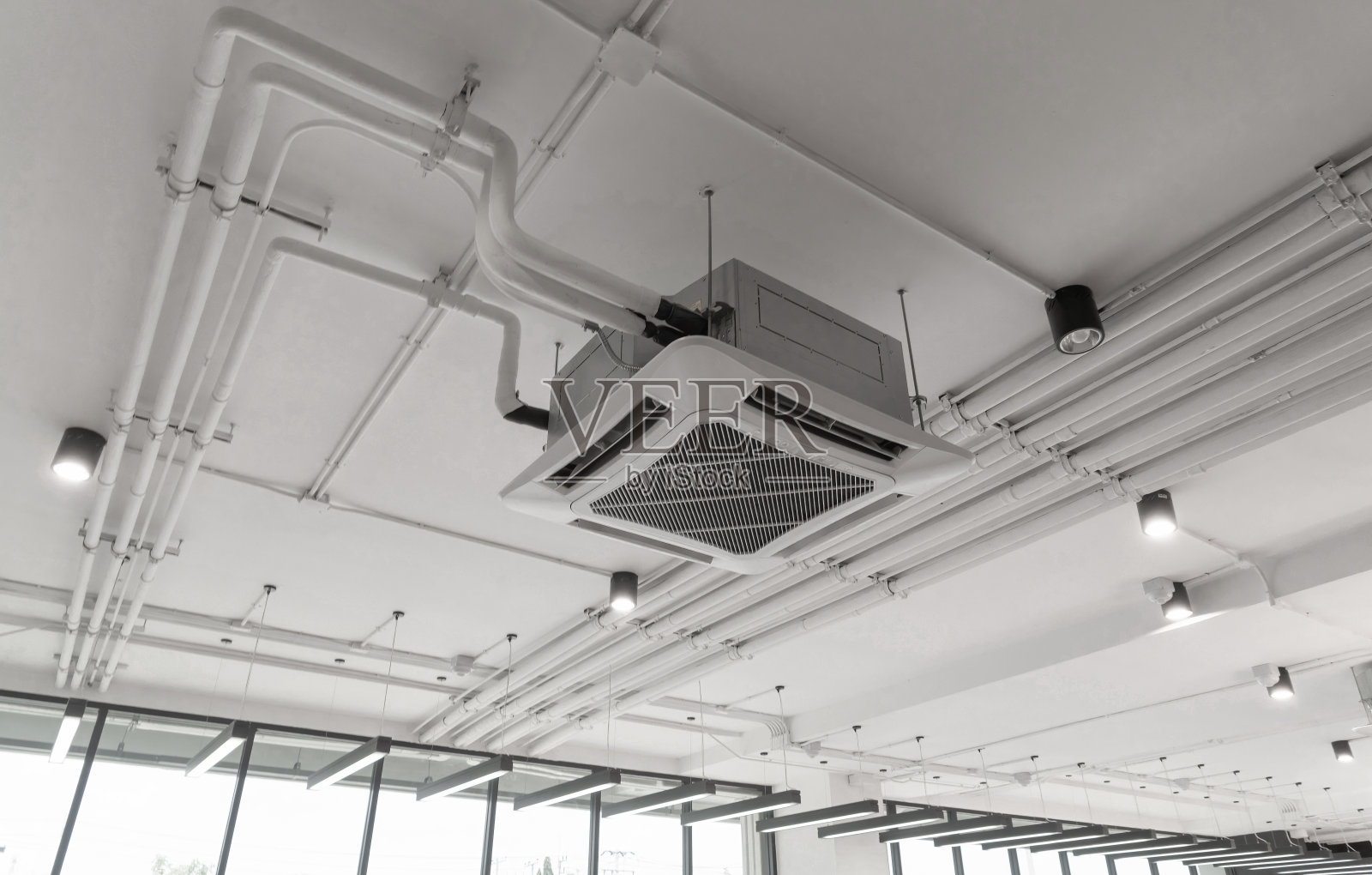 现代白色吊顶安装盒式空调在办公楼系统中工作。通风式压缩机。照片摄影图片