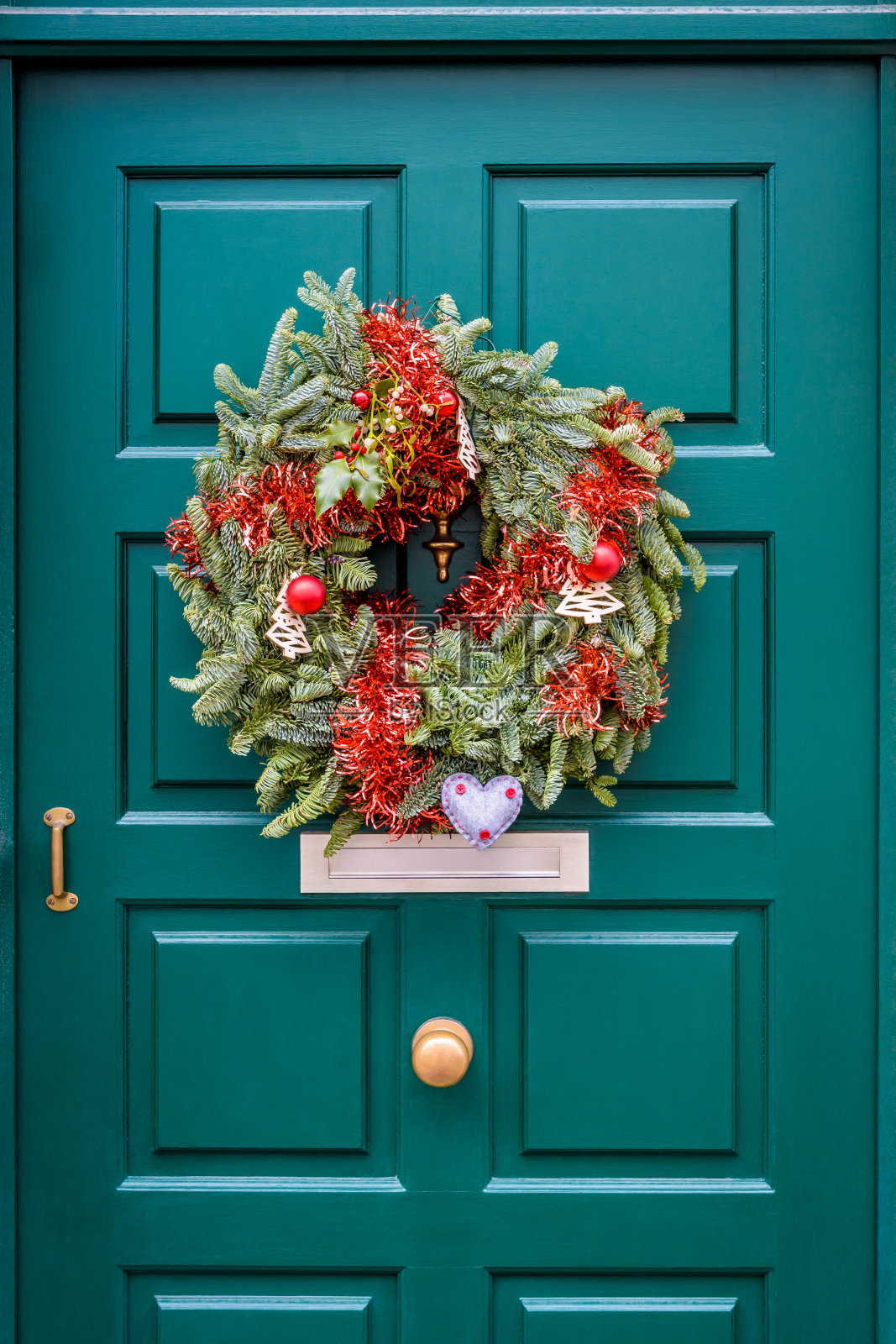 圣诞节的皇冠挂在绿色的前门与线材。照片摄影图片