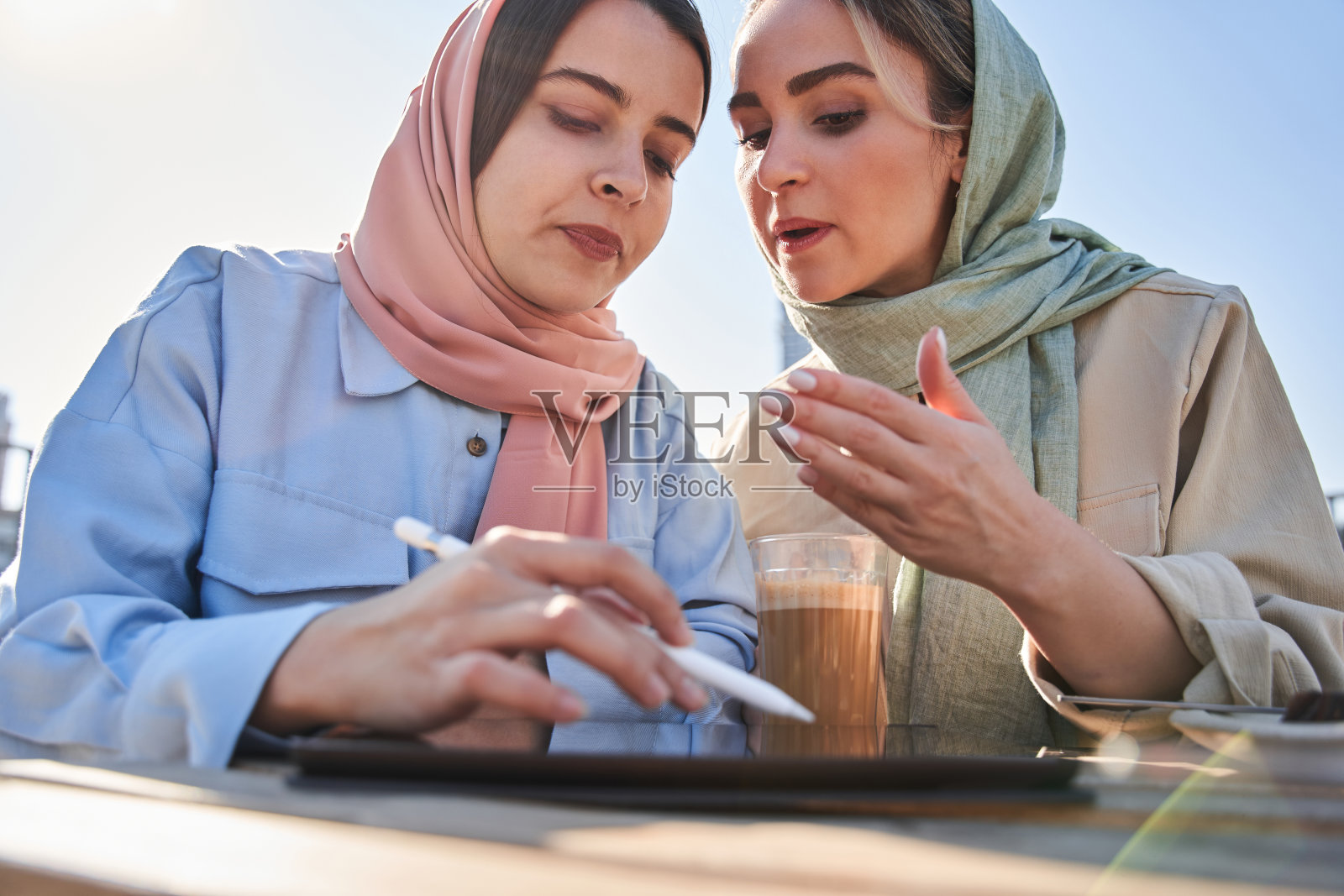一位伊斯兰妇女一边讨论一边向她的女同事打手势并给出建议照片摄影图片