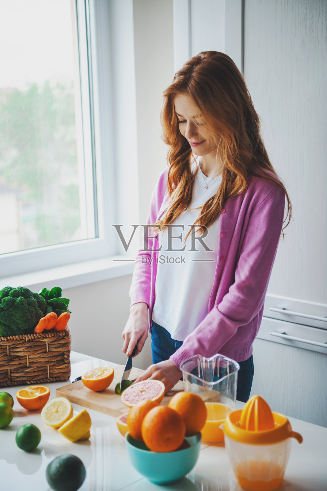 红头发的女人在厨房里切健康柑橘汁所需的原料。健康的生活方式。照片摄影图片