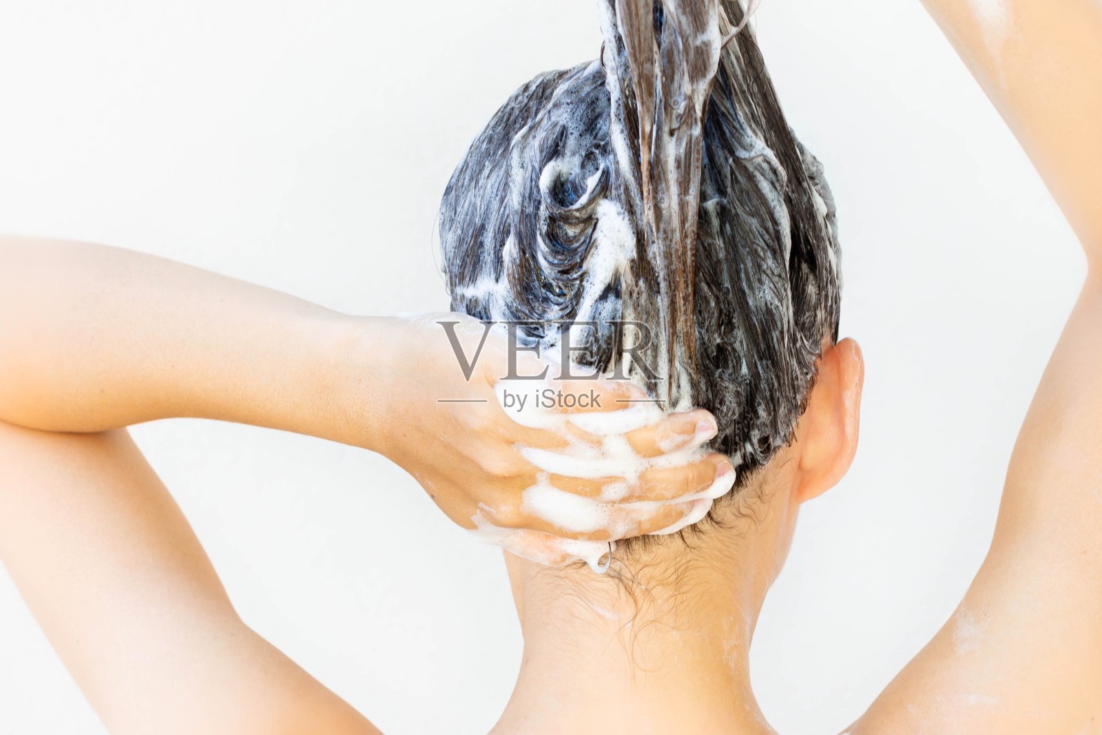 一位妇女在淋浴间清洗身体和头发。洗发水。照片摄影图片