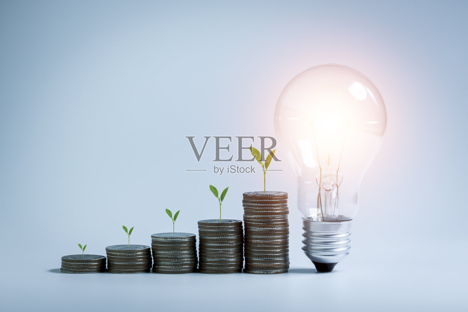 LED灯泡和叠钱硬币在木制桌子上的想法节能，省钱，银行业务的概念，投资，基金，债券，股息和利息。照片摄影图片