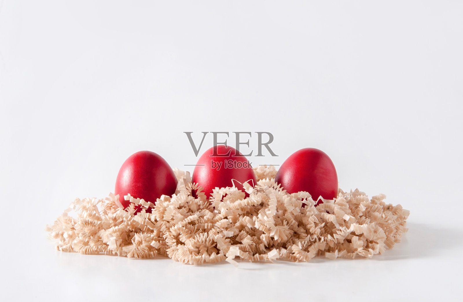 在白色背景的鸟巢里画上红色的复活节彩蛋照片摄影图片