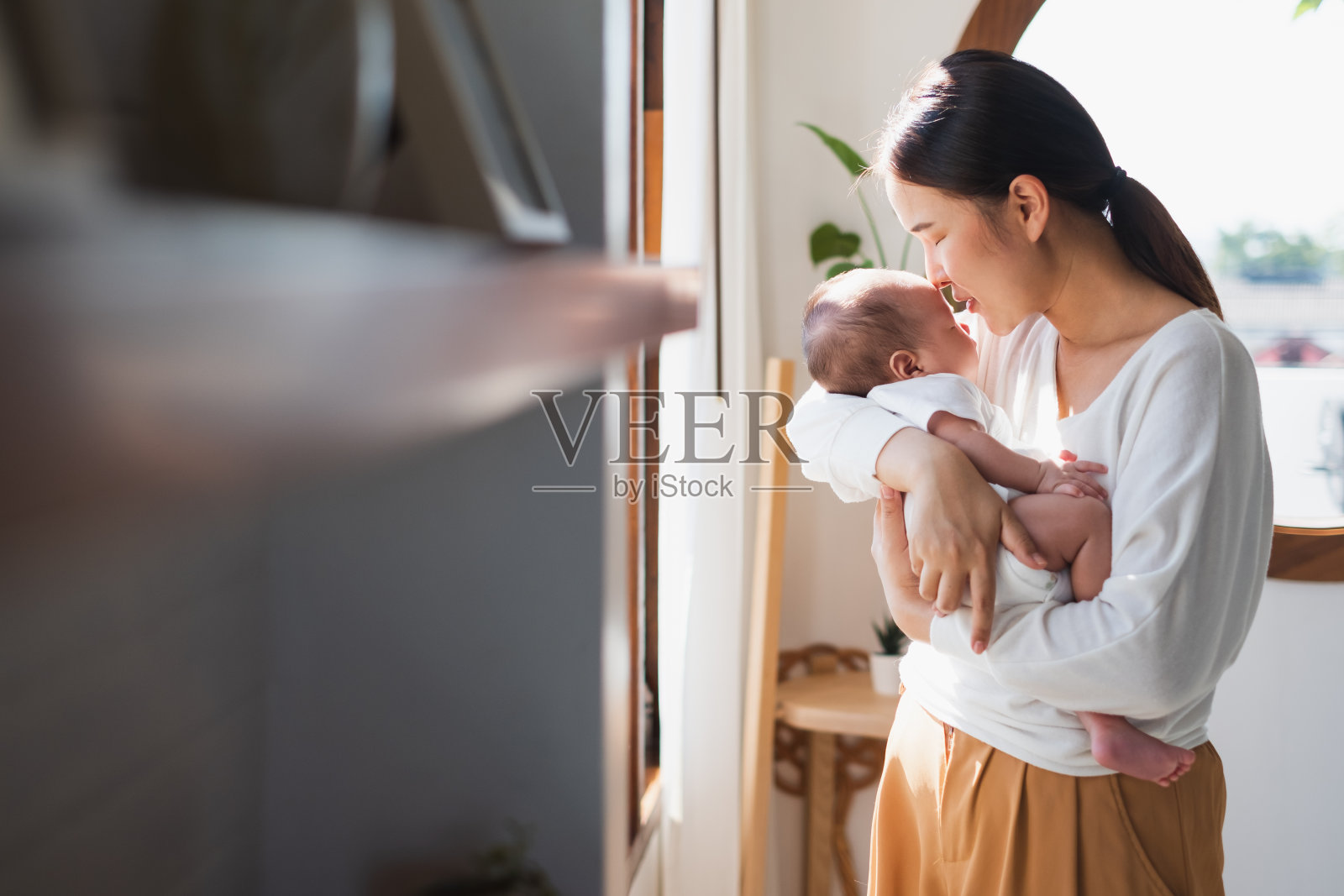 年轻的亚洲母亲抱着她刚出生的婴儿在卧室里照片摄影图片