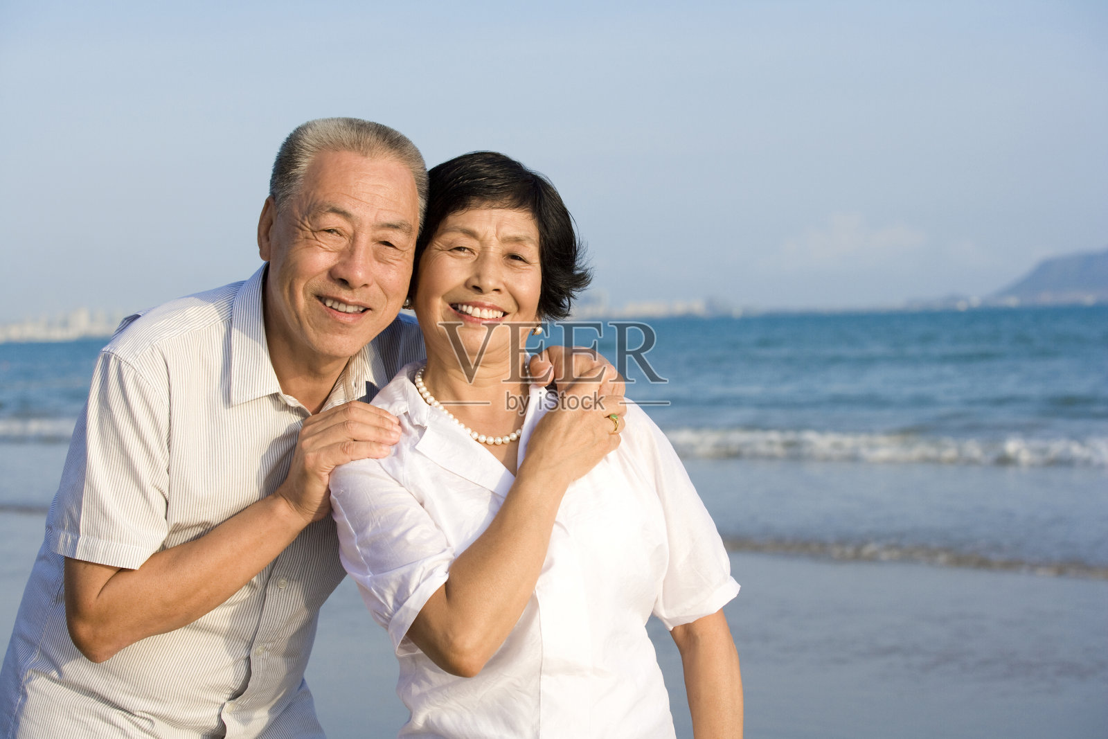 老年夫妇在海滩拥抱照片摄影图片