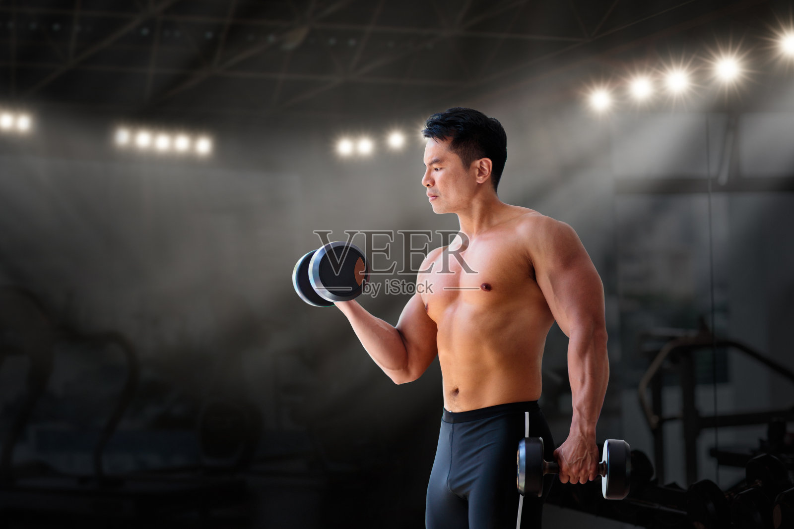 男人在健身房锻炼，健美运动员在举重照片摄影图片