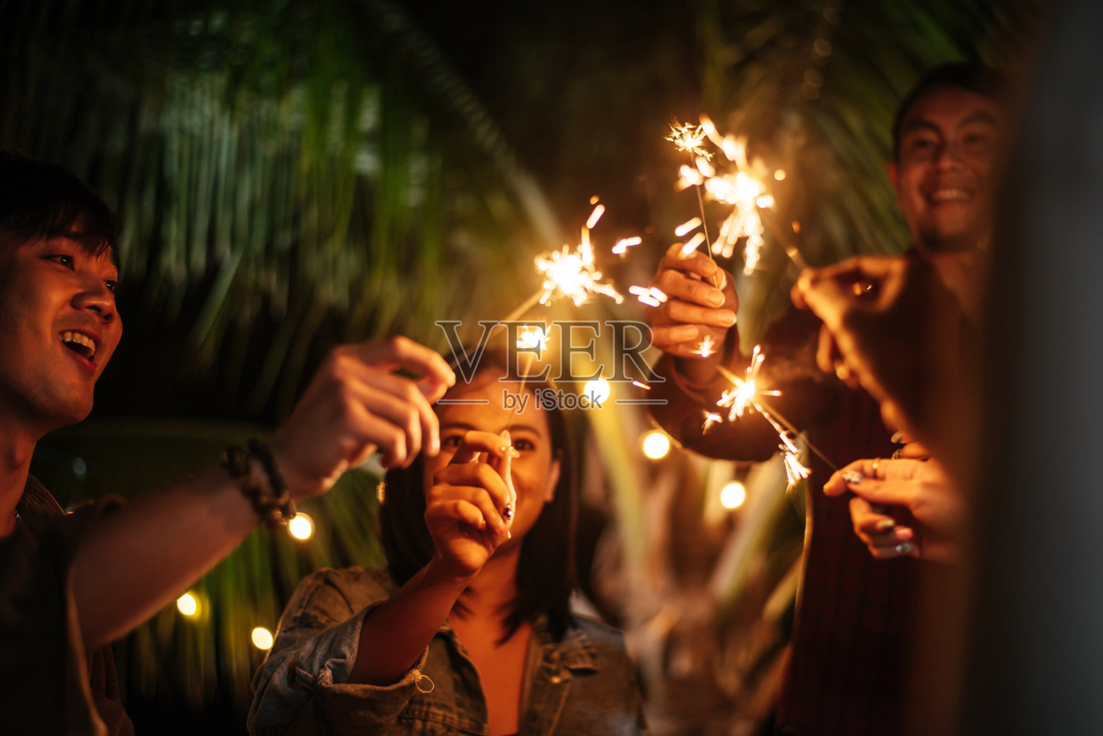 快乐的亚洲一群朋友在户外玩烟花的肖像-年轻人在晚上玩烟花-人，食物，饮料的生活方式，新年庆祝概念。照片摄影图片