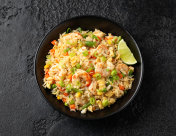 大虾炒饭，鸡蛋和蔬菜在黑碗。健康的亚洲食物。摄影图片